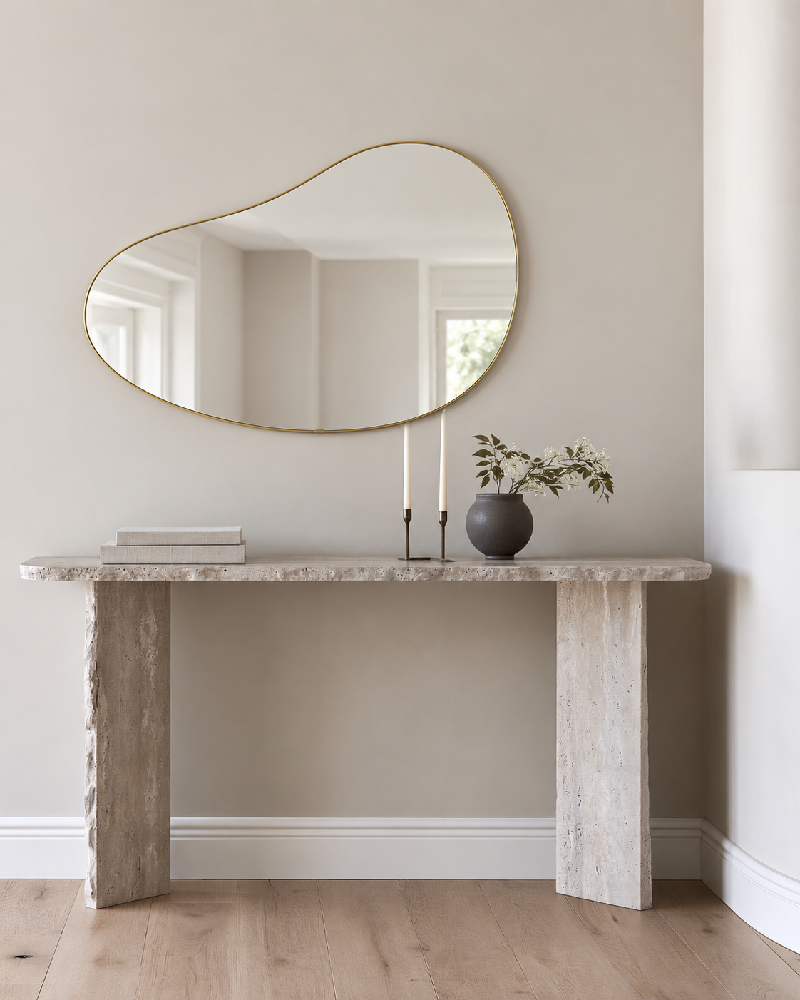 Brass Hubba Pebble mirror above a travertine console