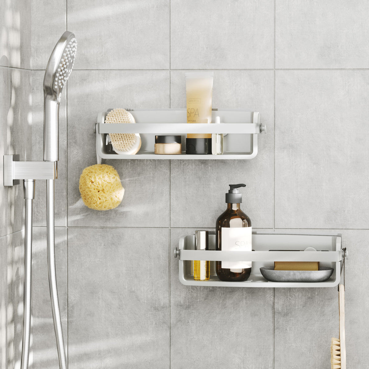 Two Umbra Flex shower bins in white in a tiled shower with bottles, soap and a sponge