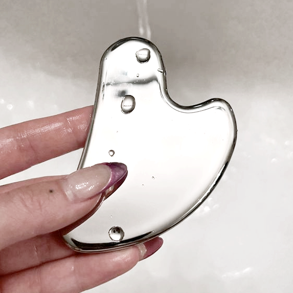 Hand holding the gua sha under water droplets
