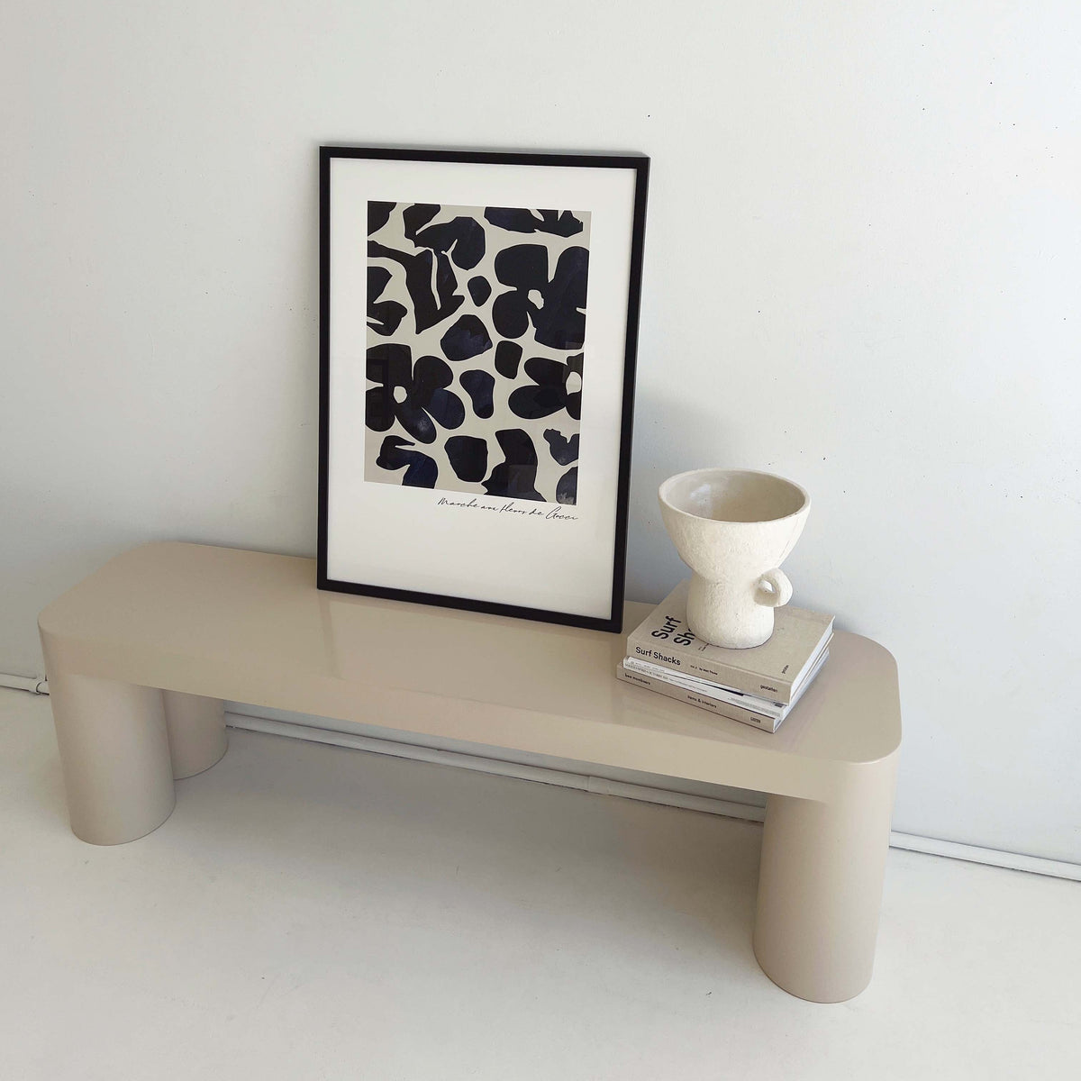 Gucci Flower Market print in navy in a black frame on a cream bench beside a vase and books