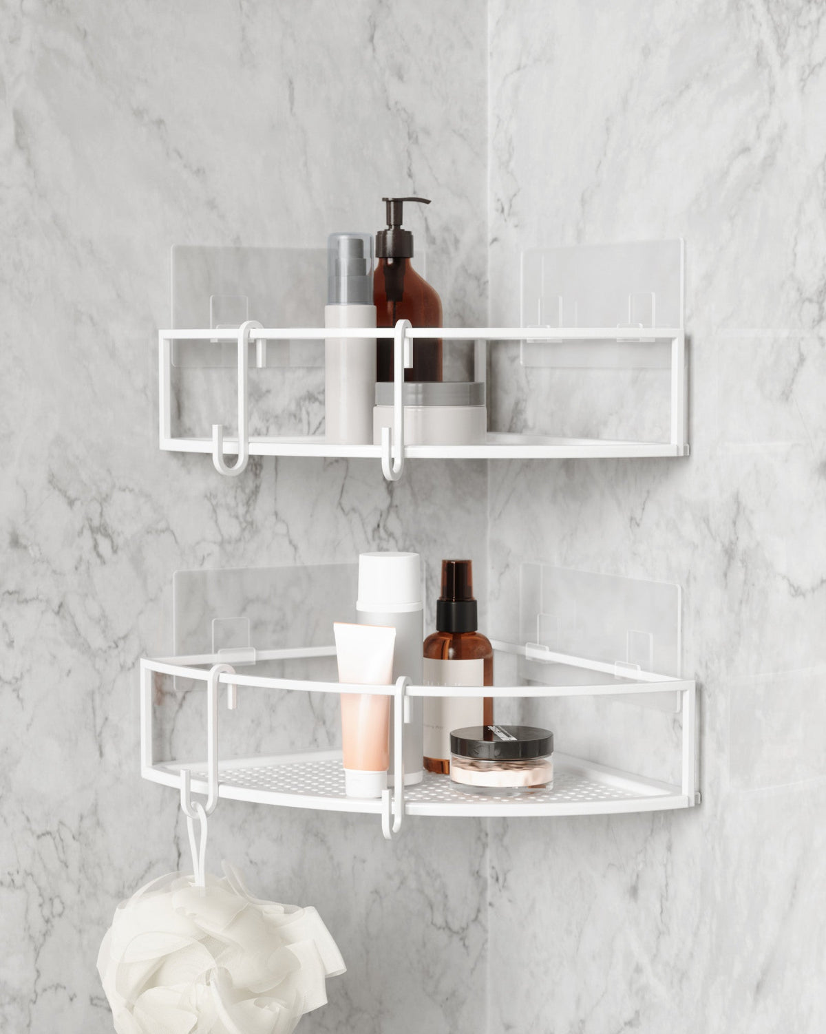Two Umbra Cubiko corner bins in white on marble tiles holding bathroom bottles