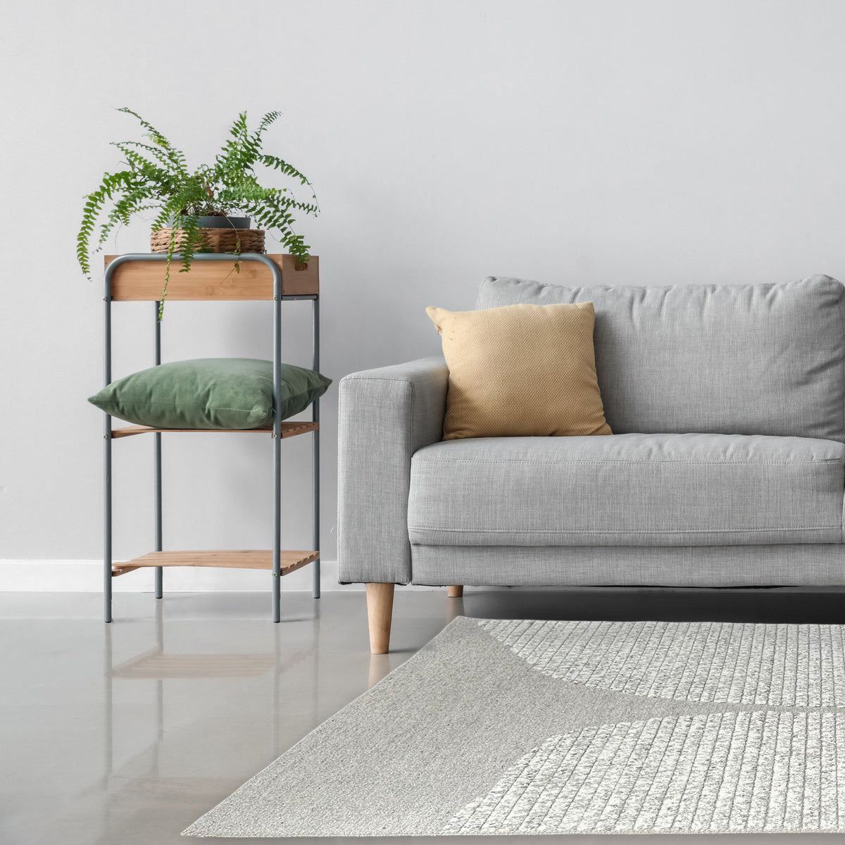 Grey and ivory curved rug beside a light grey sofa with a metal shelf and potted fern