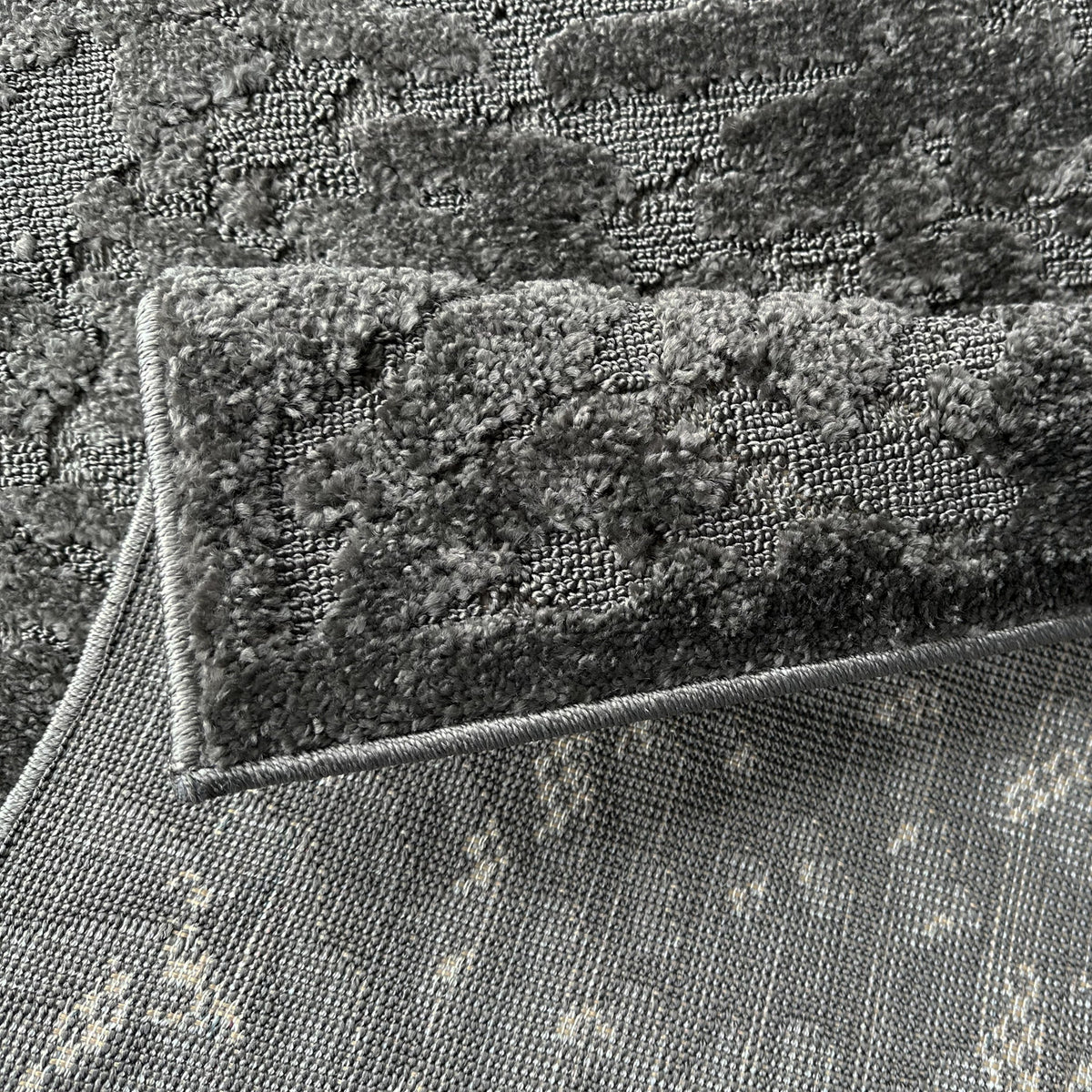 Dark grey rug folded back to show the woven backing
