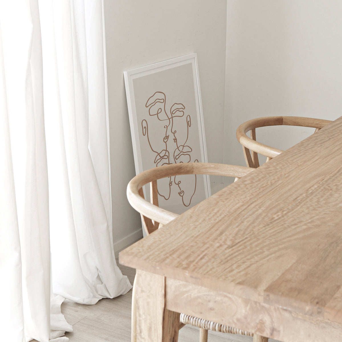 Imperfectly Perfect natural print in a white frame above a timber dining table with wishbone chairs