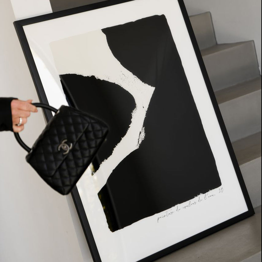 Close view of the Ink print in black in a black frame held with a quilted handbag