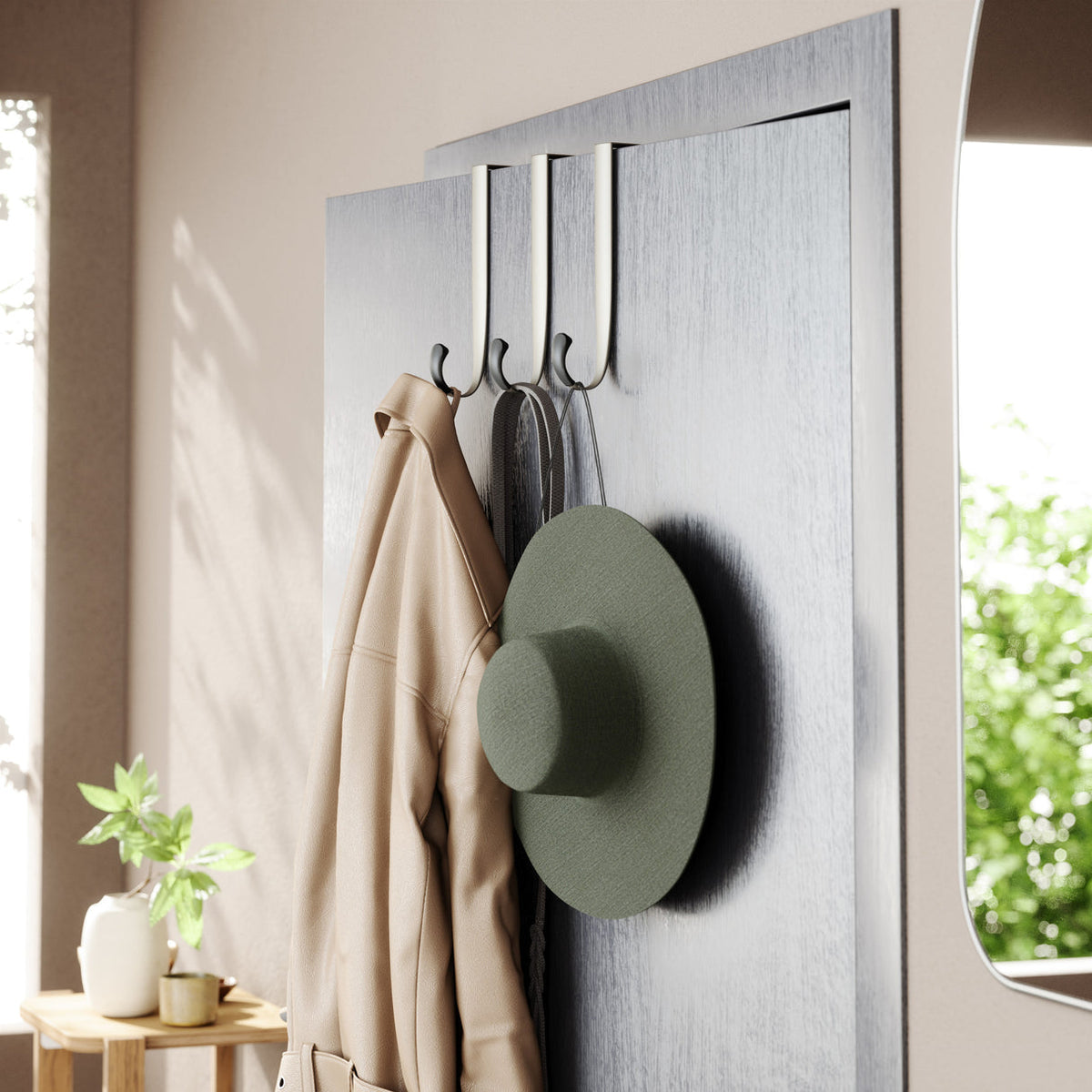 Umbra Schnook over-the-door hooks on a panelled door with a coat, bag and hat