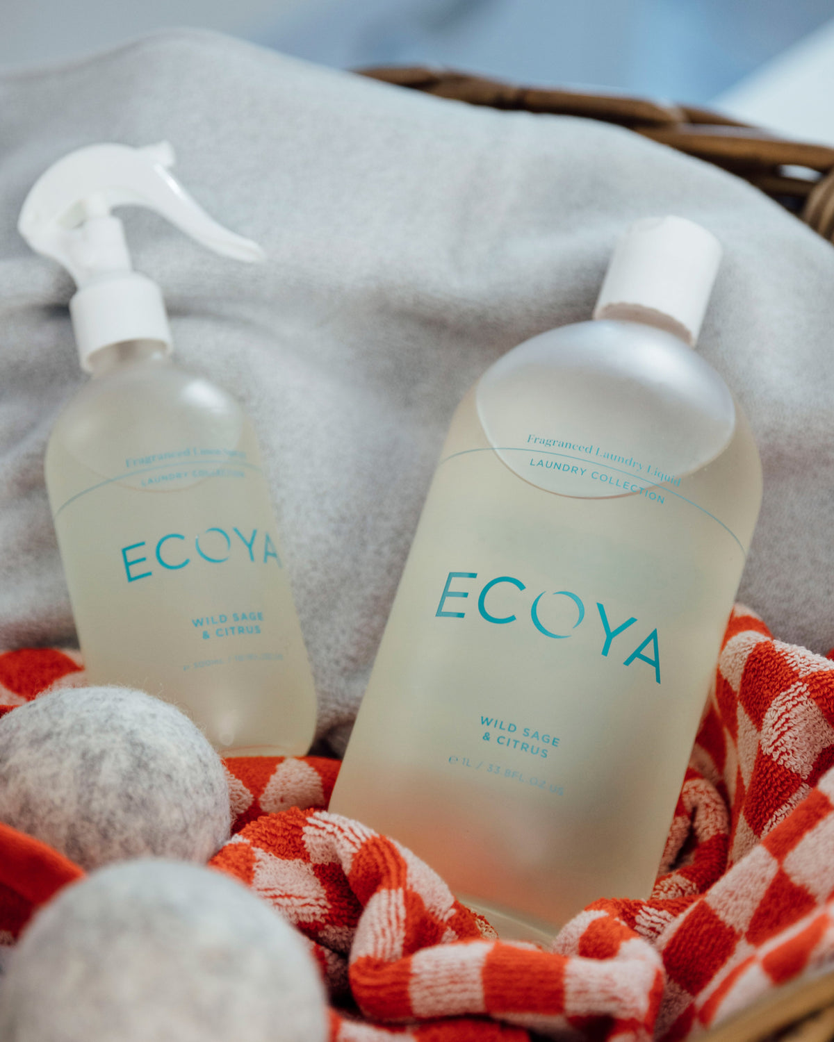Ecoya Wild Sage and Citrus linen spray and laundry liquid on a grey blanket with dryer balls