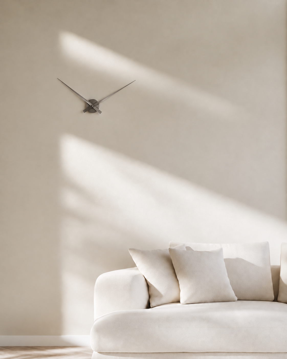 Little Big Time Wall Clock in metallic dark grey, large, on a warm white wall above a cream sofa
