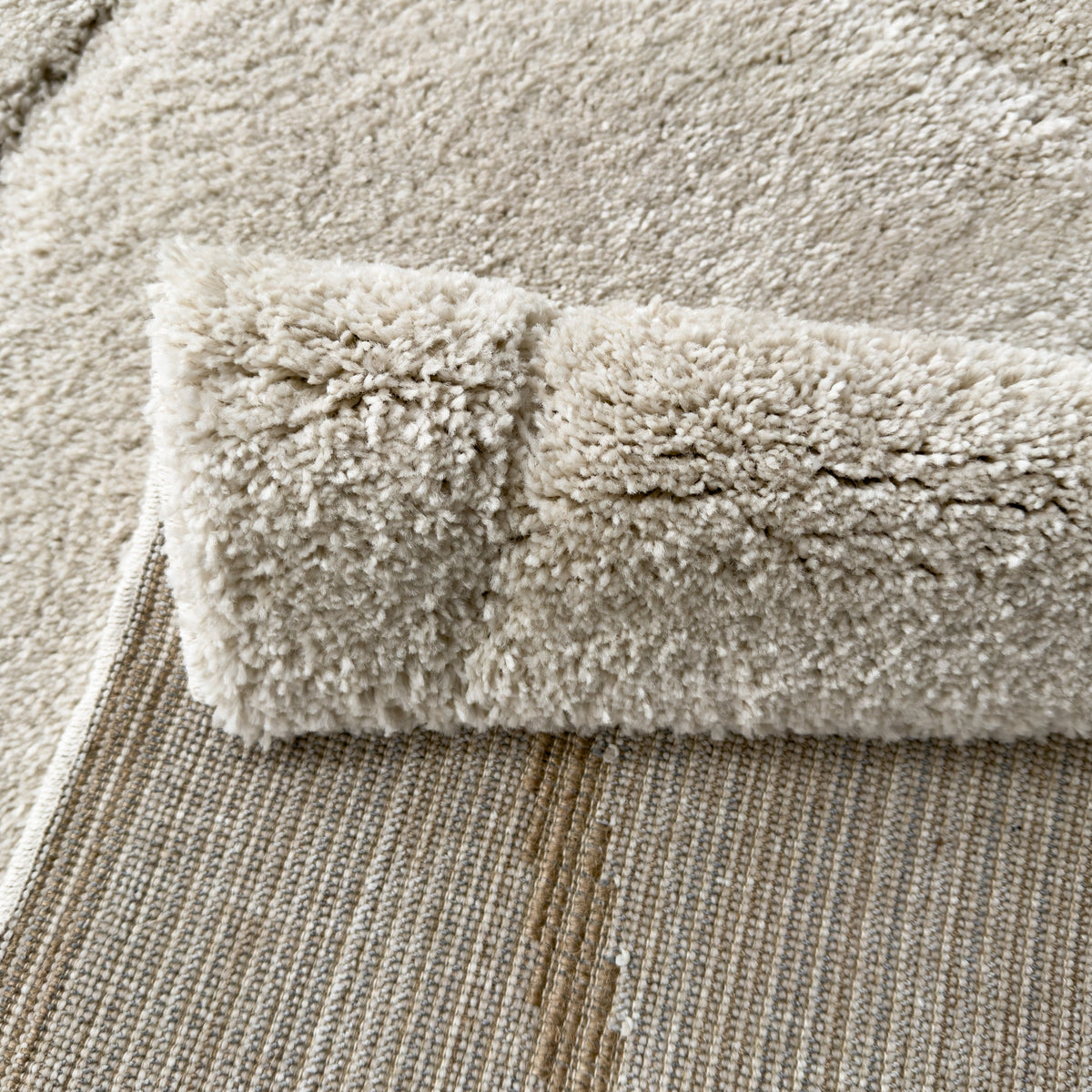 White plush rug folded back to show the woven backing