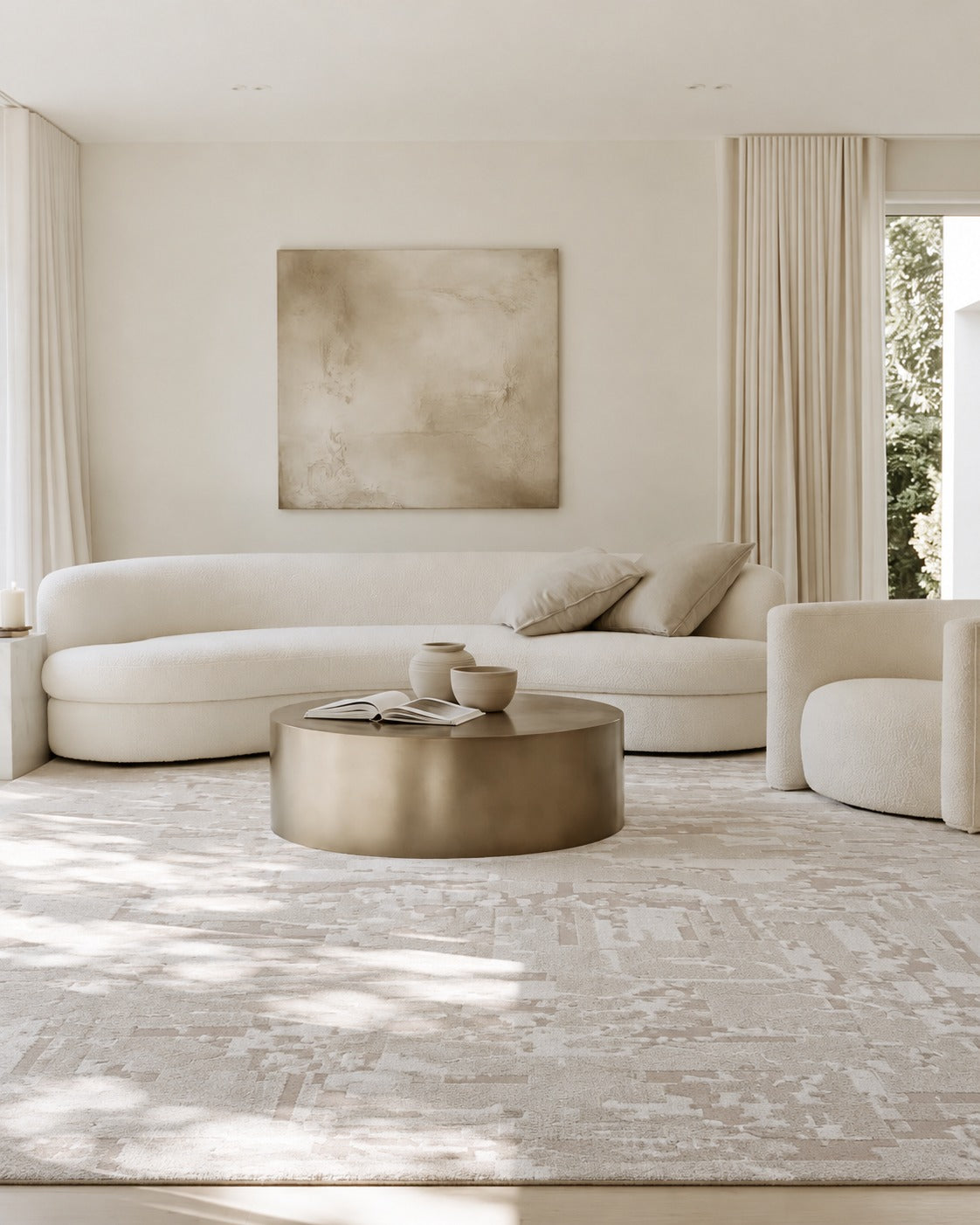 Luma Modern Neutral Rug under a round brass drum coffee table with a curved cream boucle sofa and linen curtains
