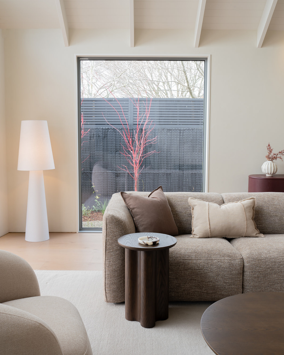 Living room with the Brown Oak Luma Side Table beside a textured sofa, a white floor lamp and a tall window