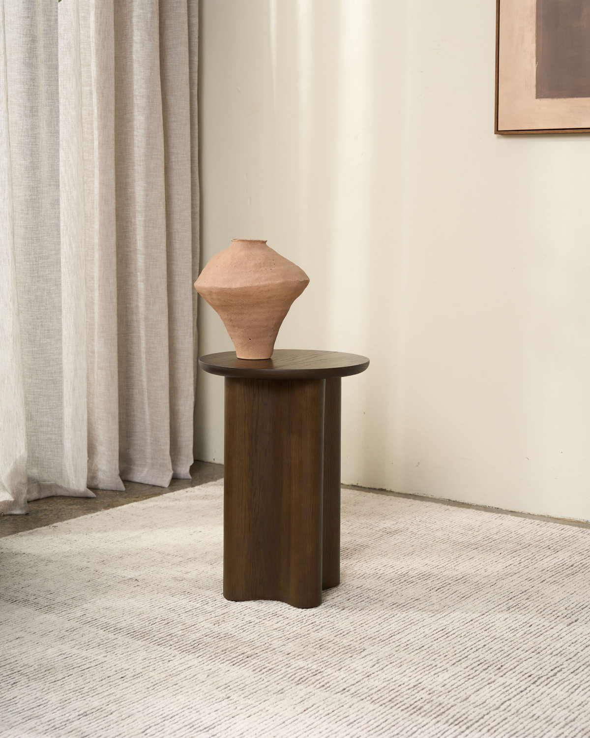 Brown Oak Luma Side Table with a terracotta clay vase on top, beside linen curtains