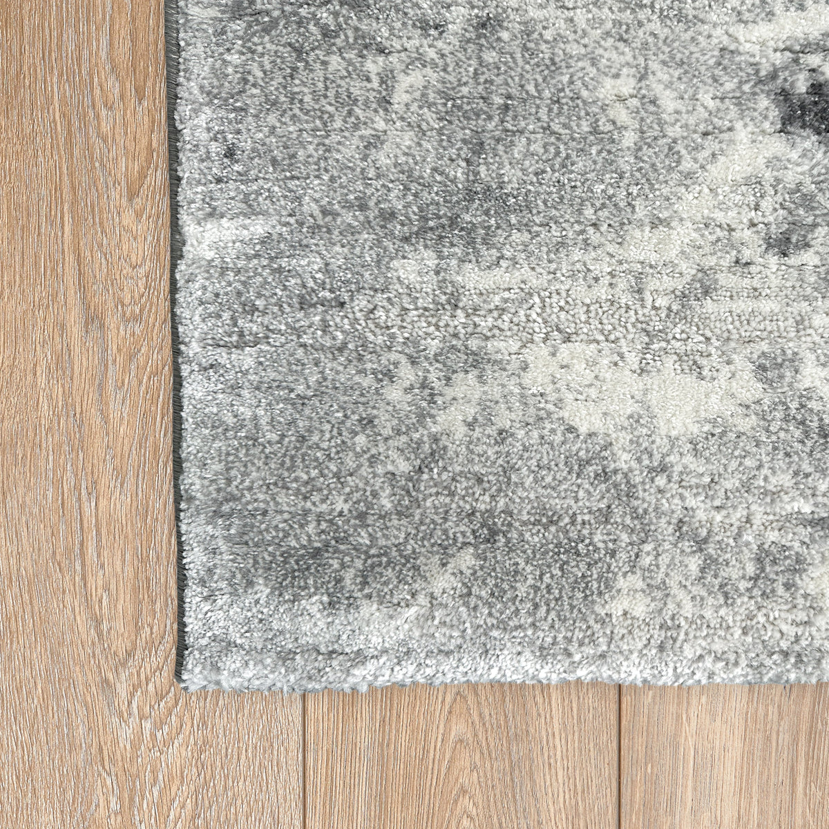 Corner of the grey abstract rug on a light timber floor
