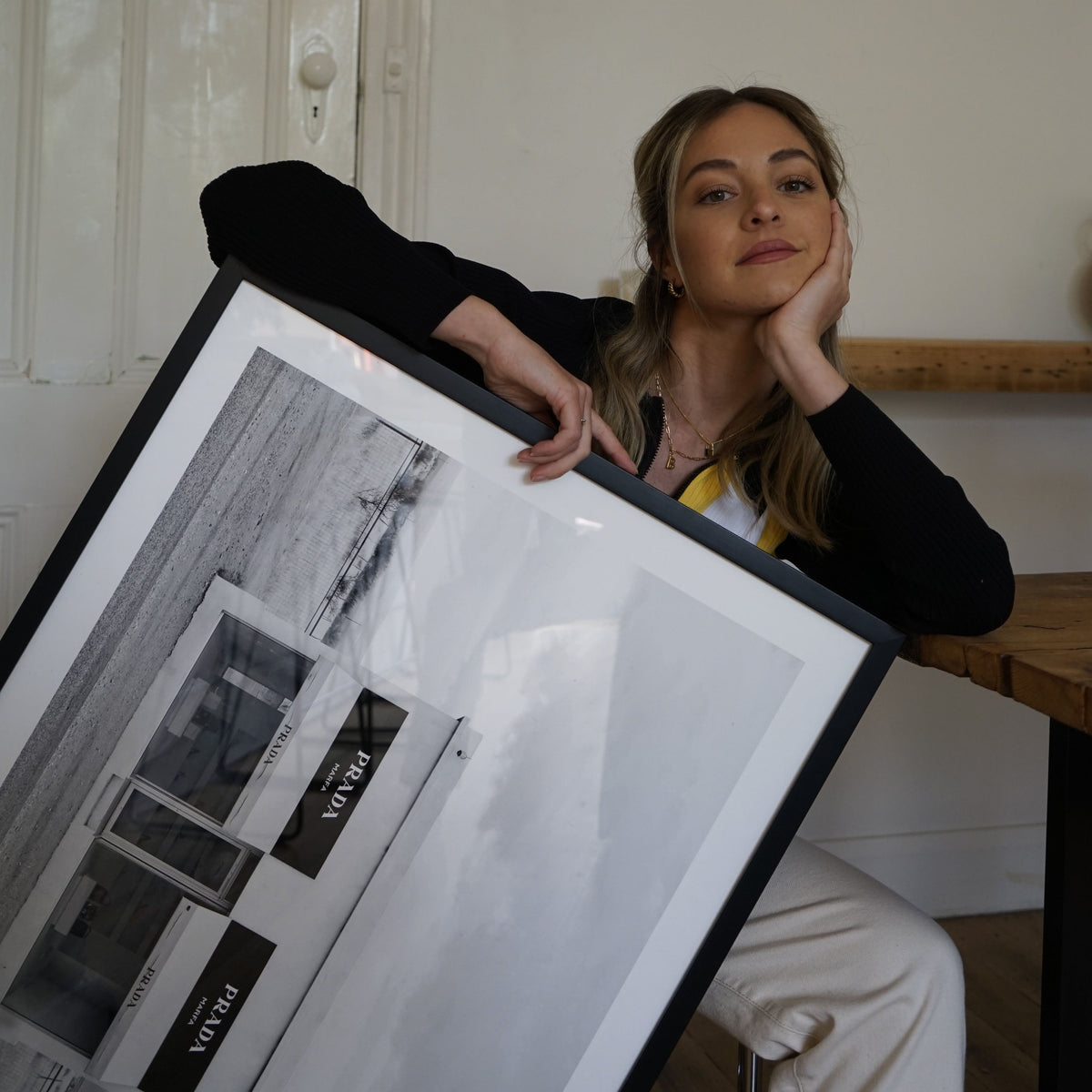 Woman leaning on the Marfa print in a black frame held at an angle