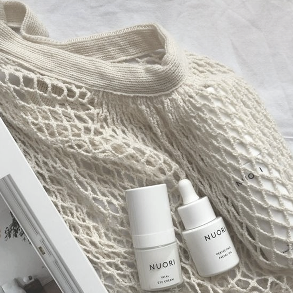 Close up of the cream string mesh and ribbed handle beside two plain white skincare bottles