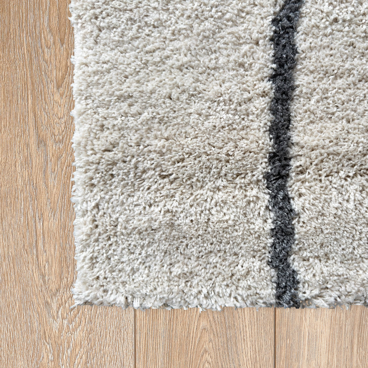 Corner of the white and black rug on a timber floor