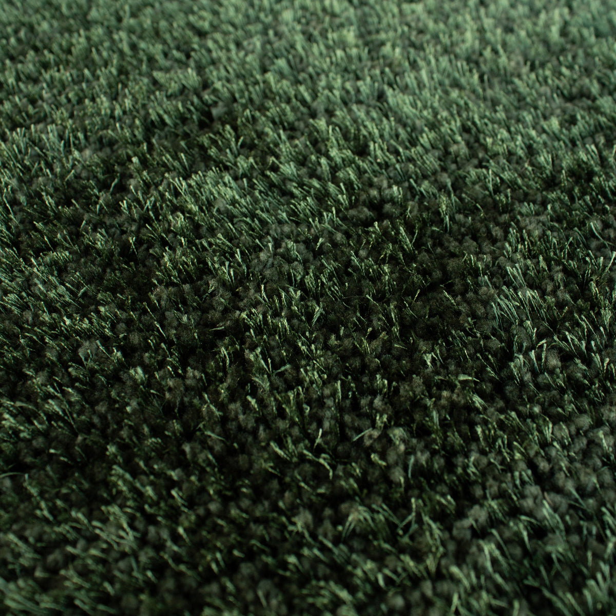 Close view of the forest green shaggy pile in thick and thin yarns