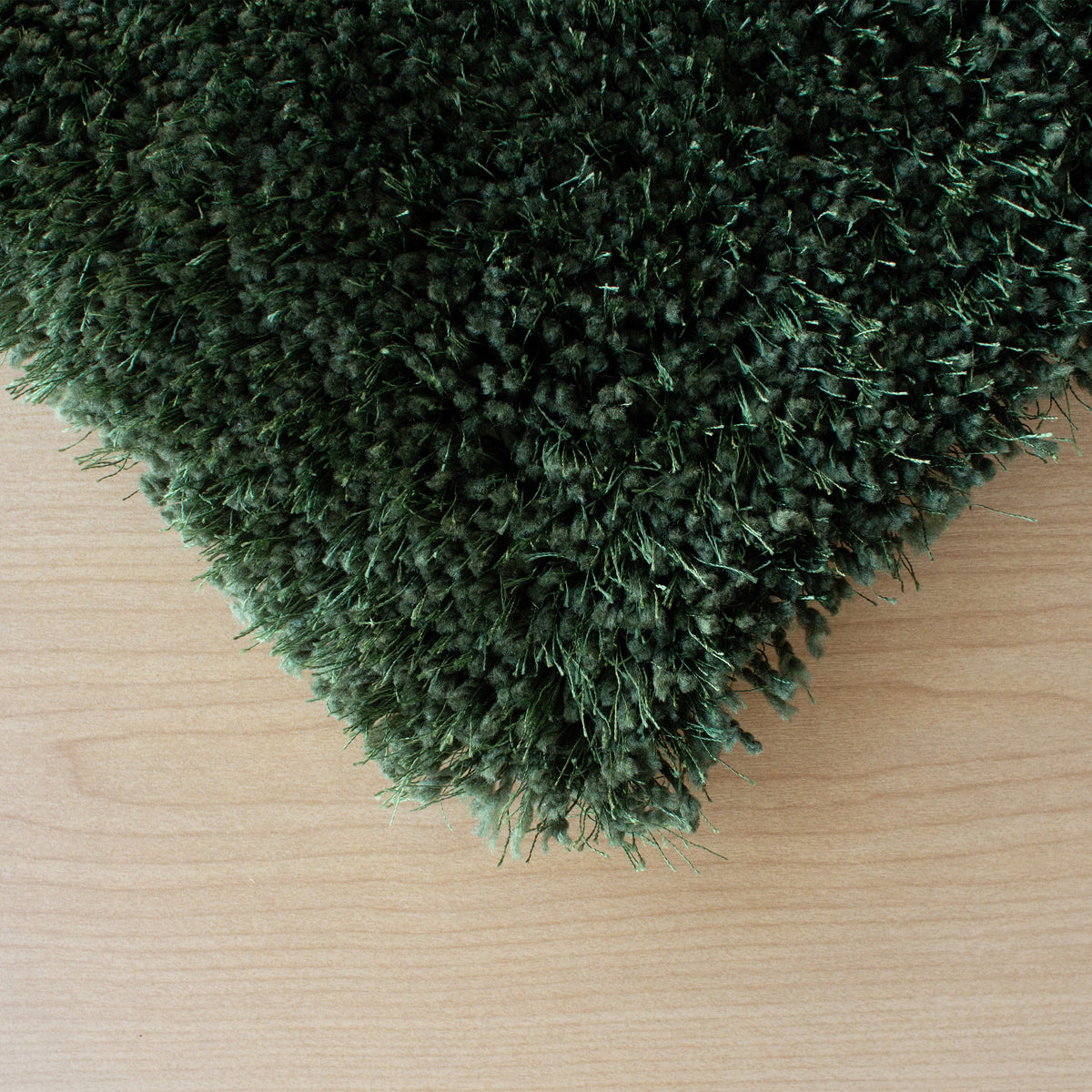 Corner of the forest green shag rug on a pale timber floor