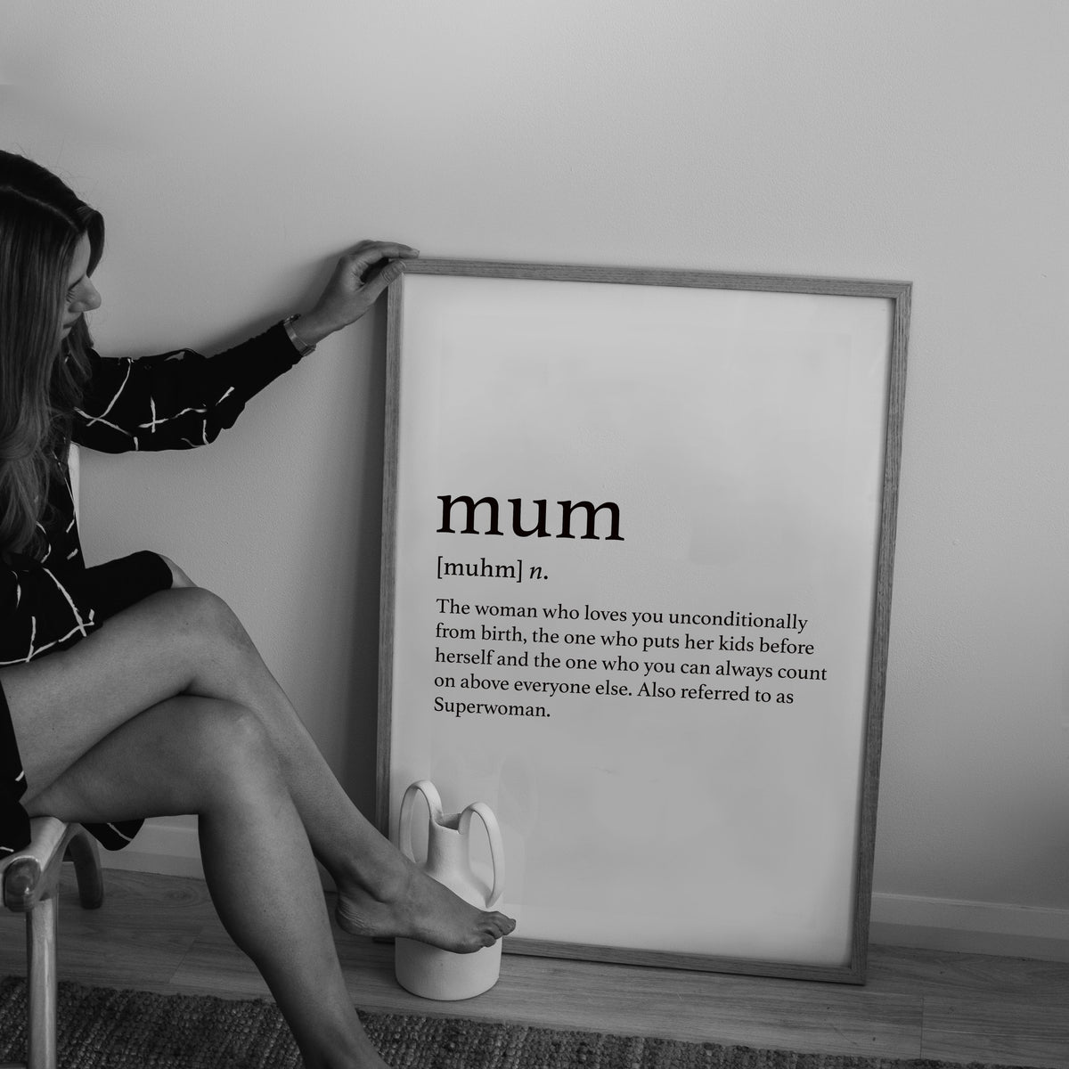 Woman seated beside the Mum print in a natural frame, black and white photo