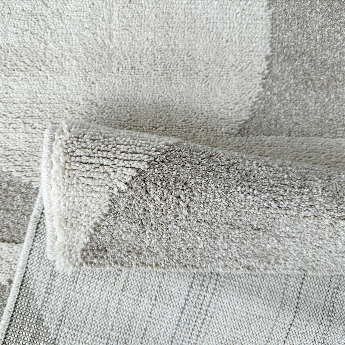 Beige geometric rug folded back to show its woven backing