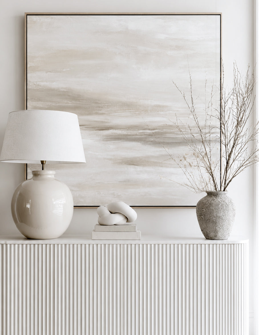 Nerina sage vase with bare branches on a fluted white sideboard beside a ceramic lamp and neutral canvas