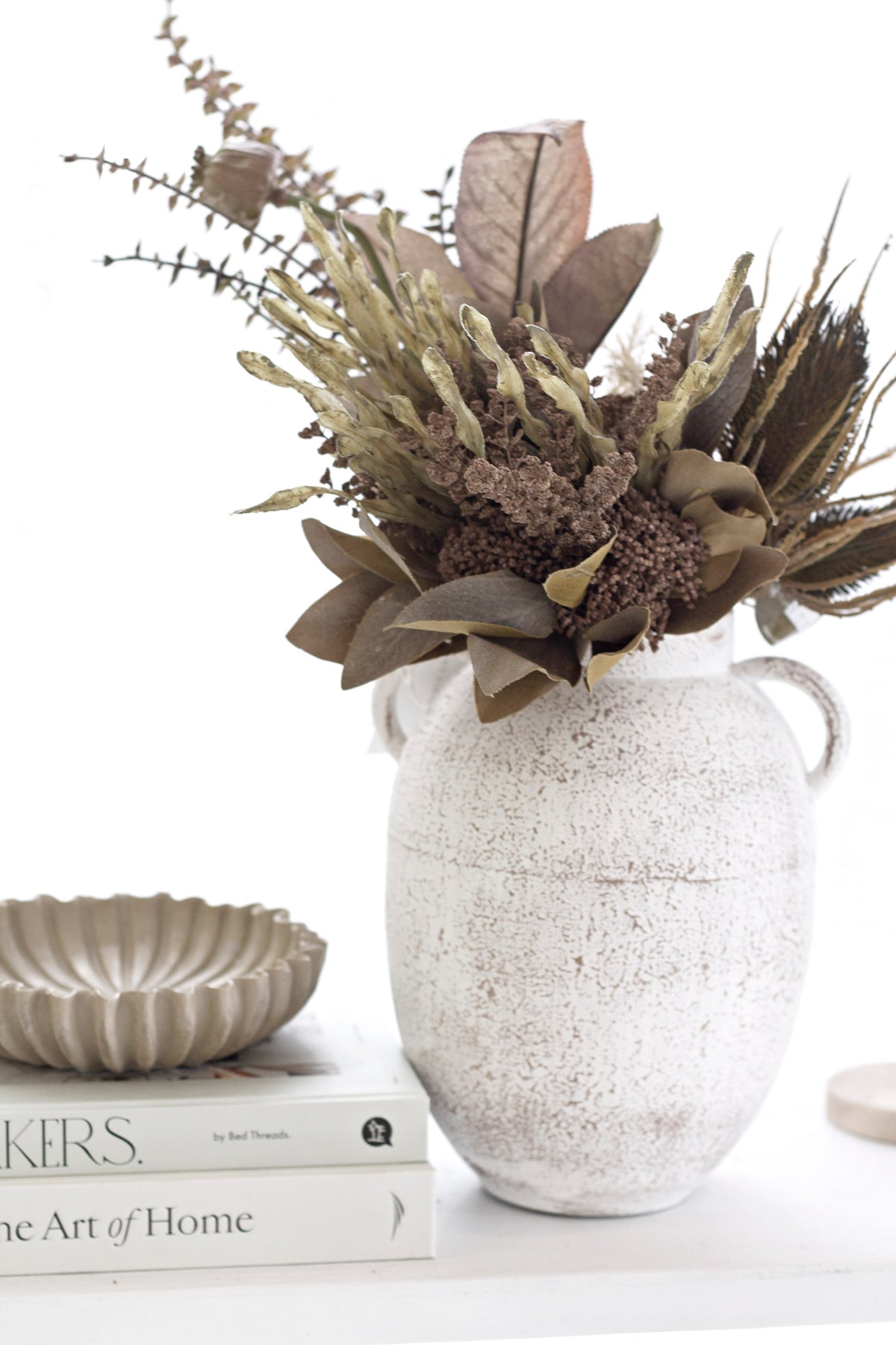 Bowl styled on console table with books and ceramic vase with dried florals