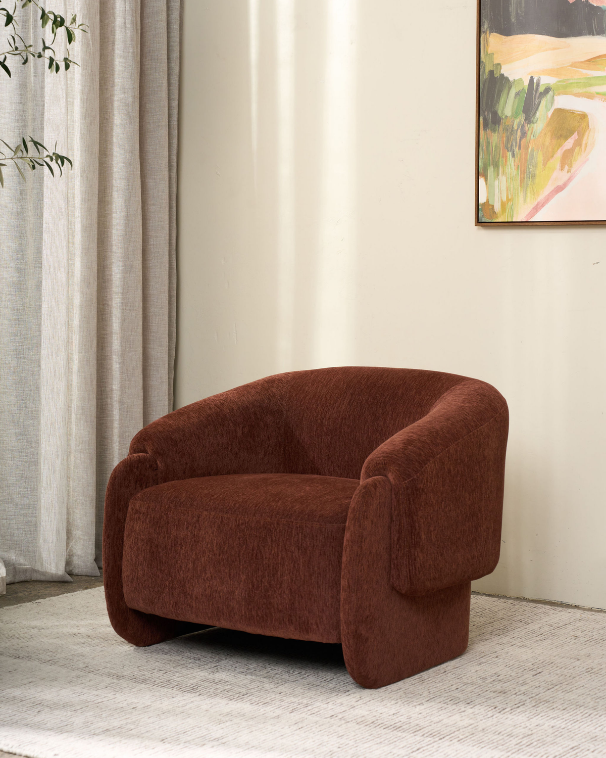 Umber armchair on a pale rug beside linen curtains, with a landscape painting above