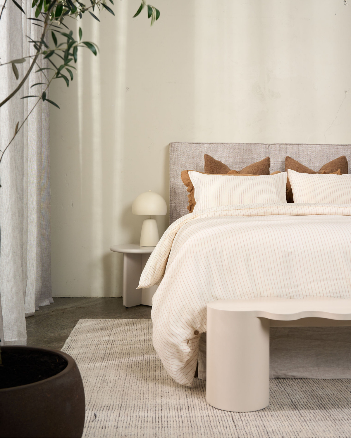 Bedroom with the cream side table as a bedside holding a mushroom lamp, beside a linen bed