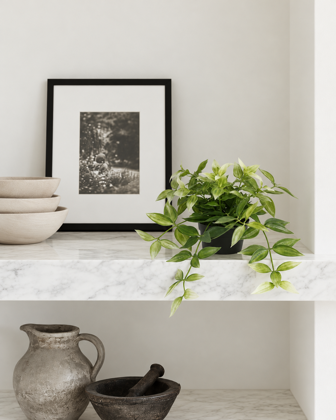 Potted faux wandering dew trailing from a marble shelf beside a framed print
