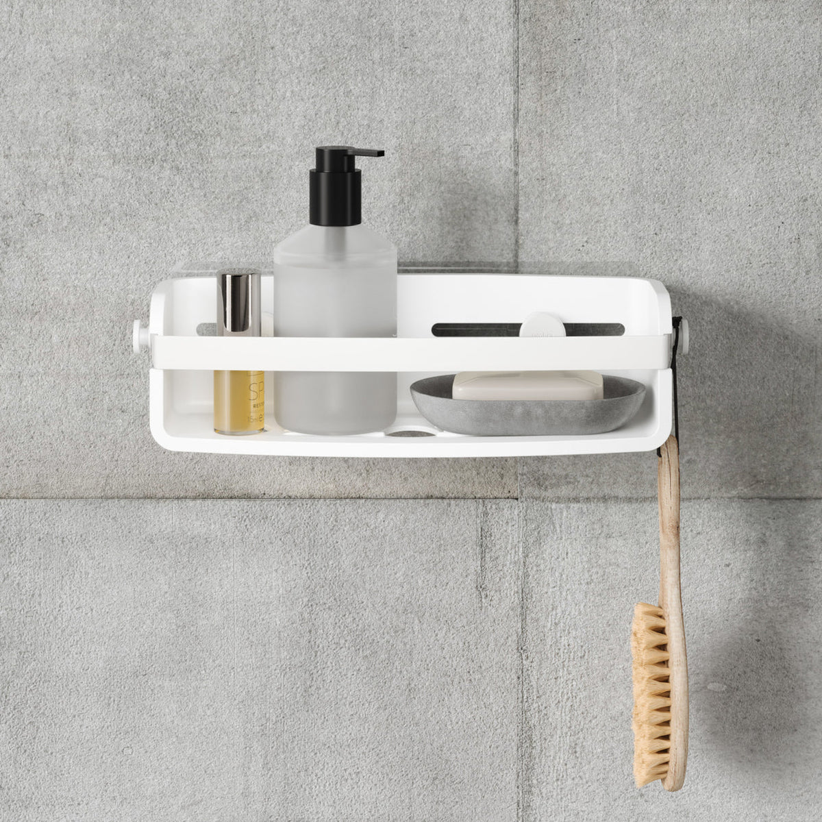 Umbra Flex adhesive shower bin in white with a soap pump and dish, brush hanging below