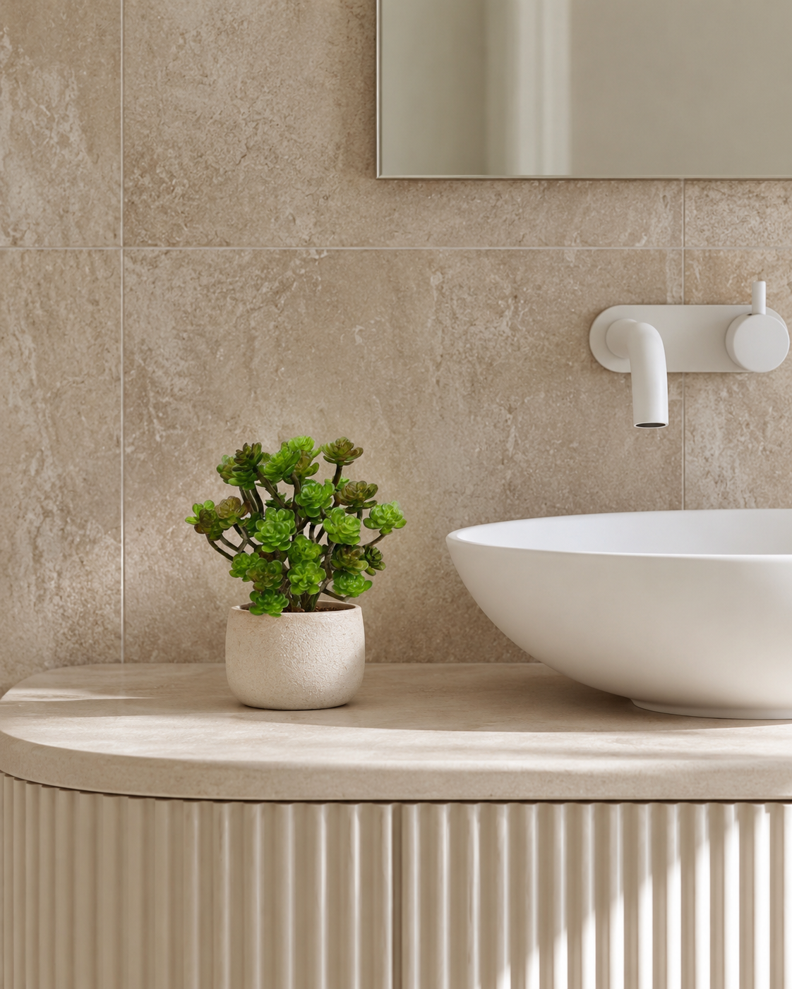 Faux succulent bush in a small stone pot on a travertine bathroom vanity
