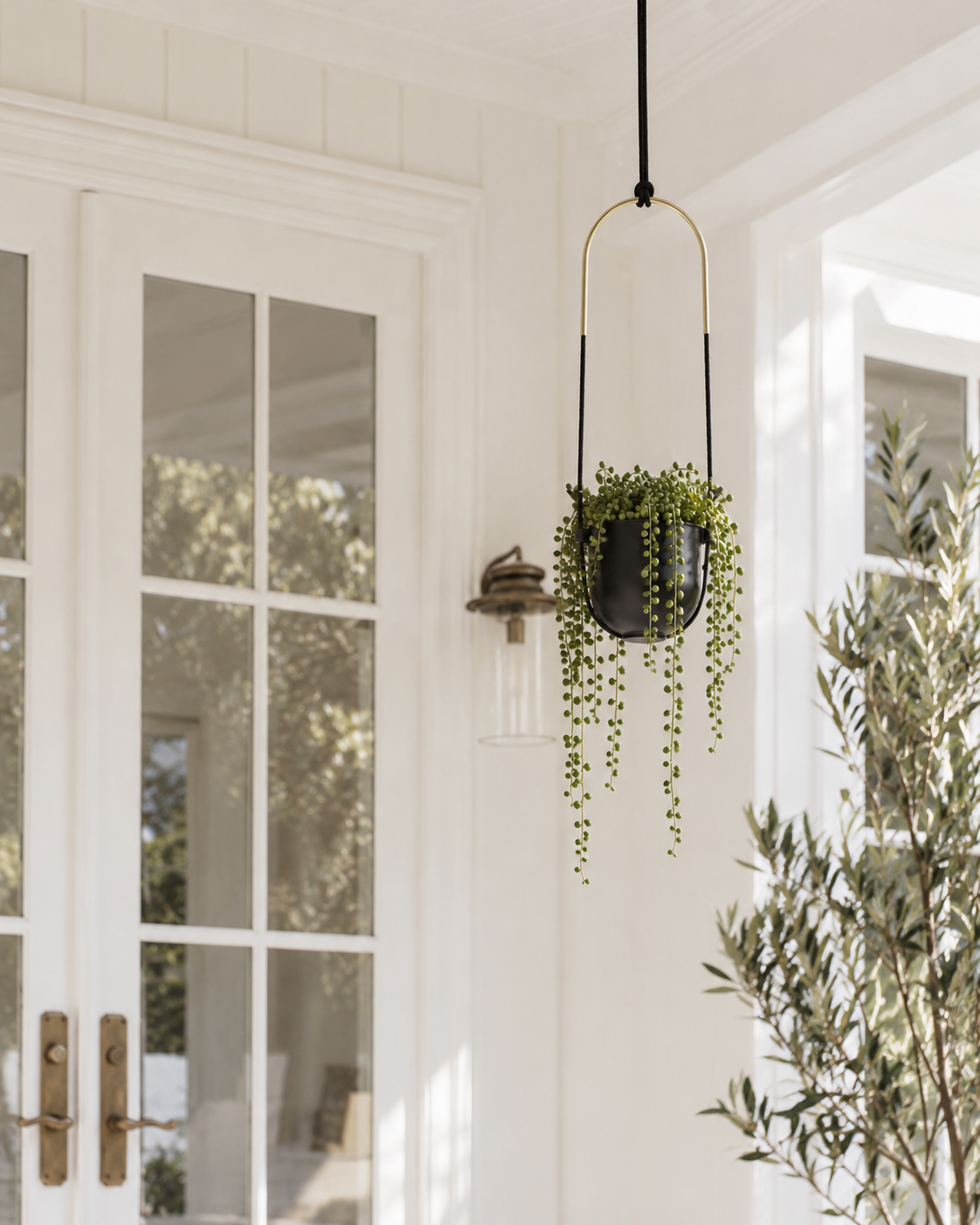 Bolo hanging planter with string of pearls on a white porch beside French doors
