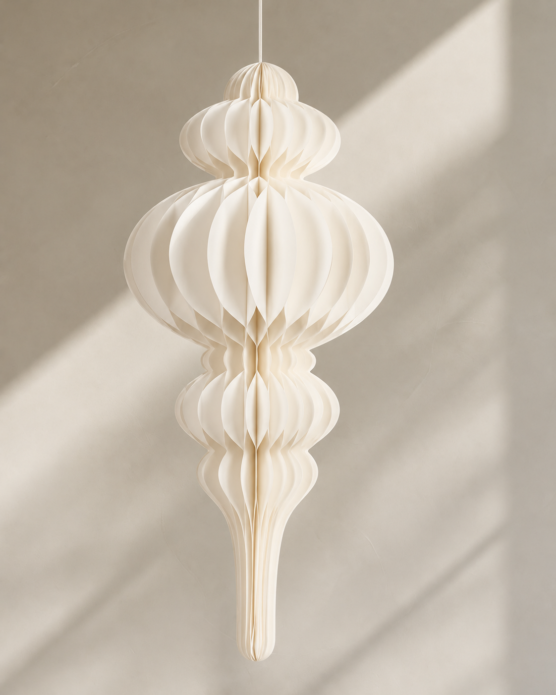 Papier Campanile off white honeycomb paper decoration hanging against a sunlit plaster wall