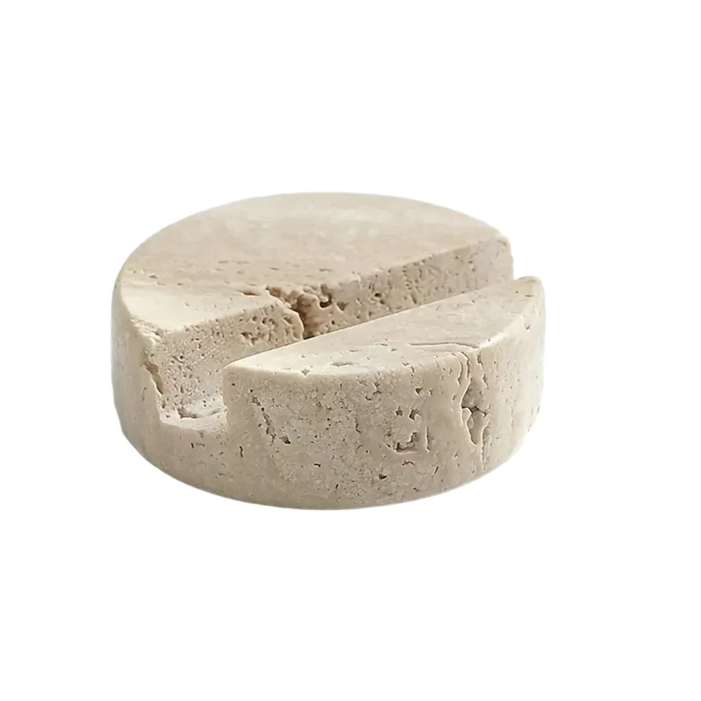 Round travertine phone stand with an angled groove on a white background