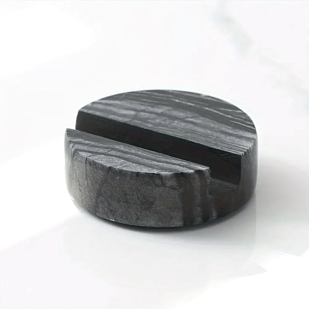 Black marble phone stand on a white marble surface