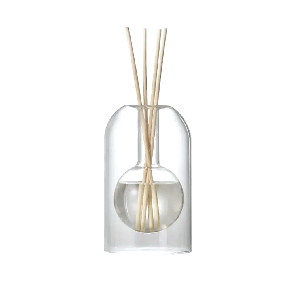 Glass reed diffuser with a rounded inner reservoir and natural reeds, on a plain background