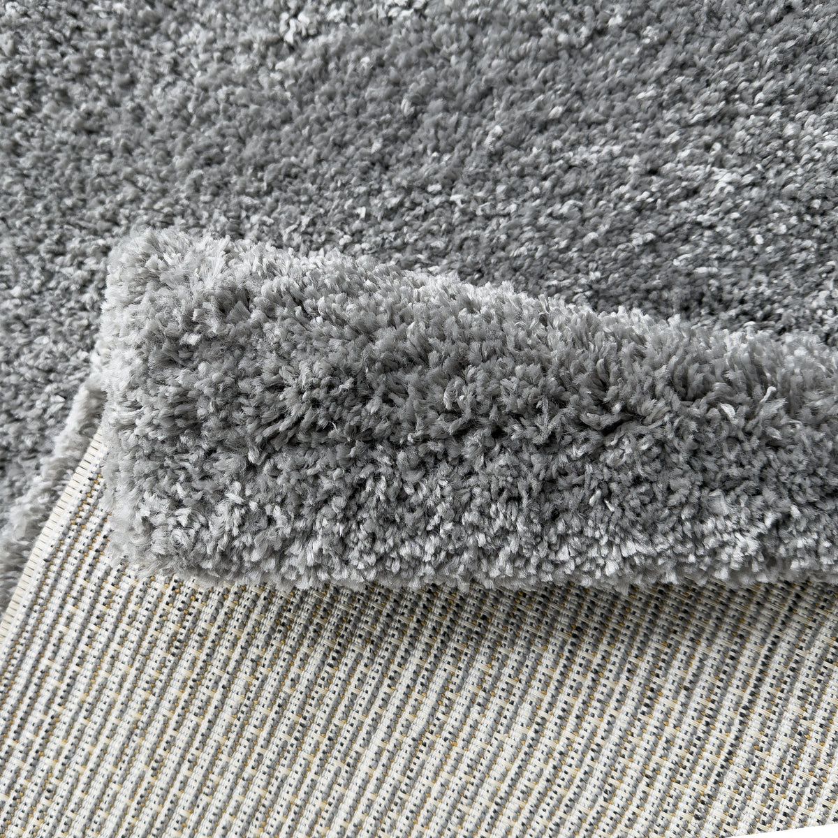 Folded corner of the grey rug showing the plush pile and woven backing