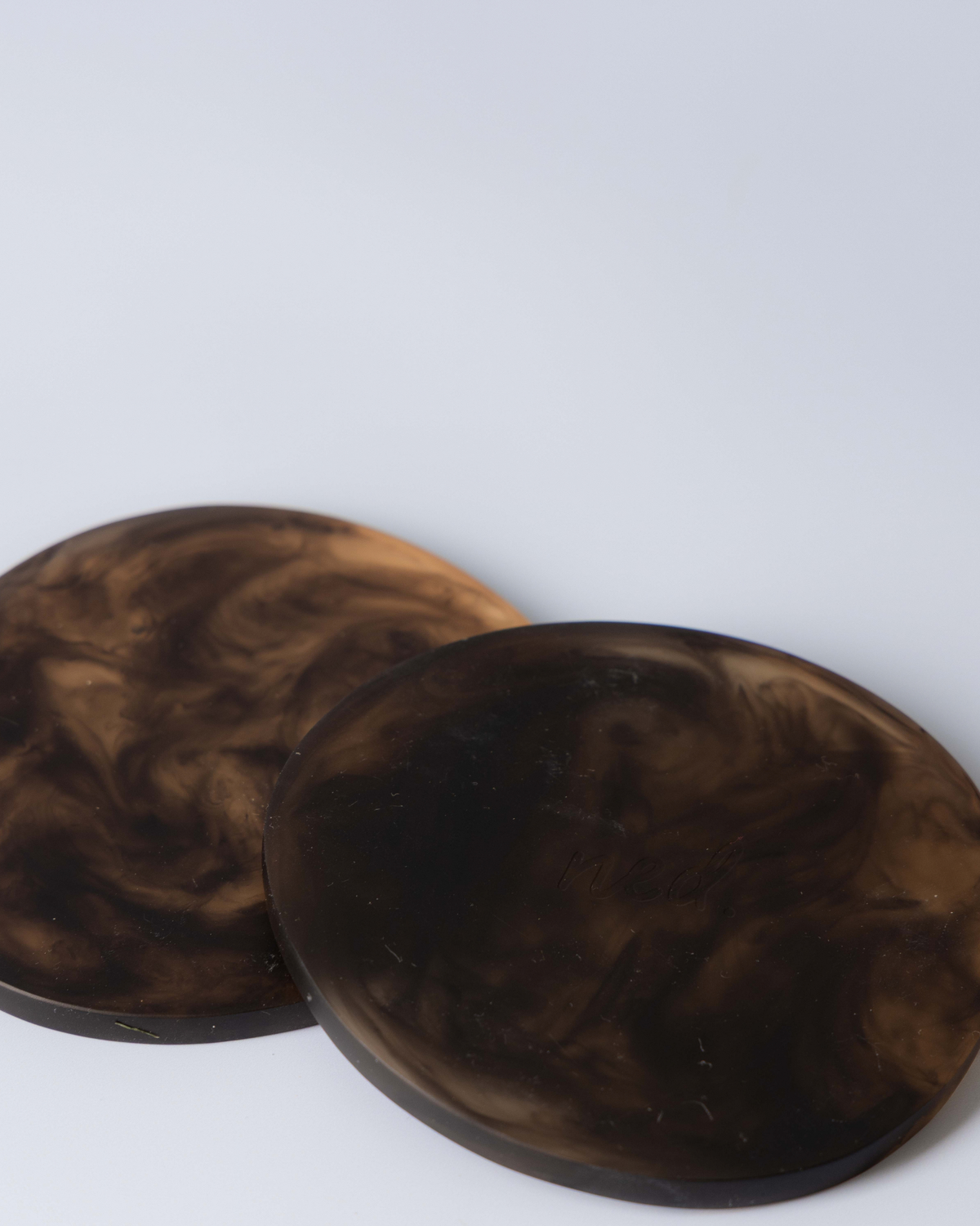 Two Chocolate resin coasters overlapping, deep brown with darker marbling, on a soft grey background