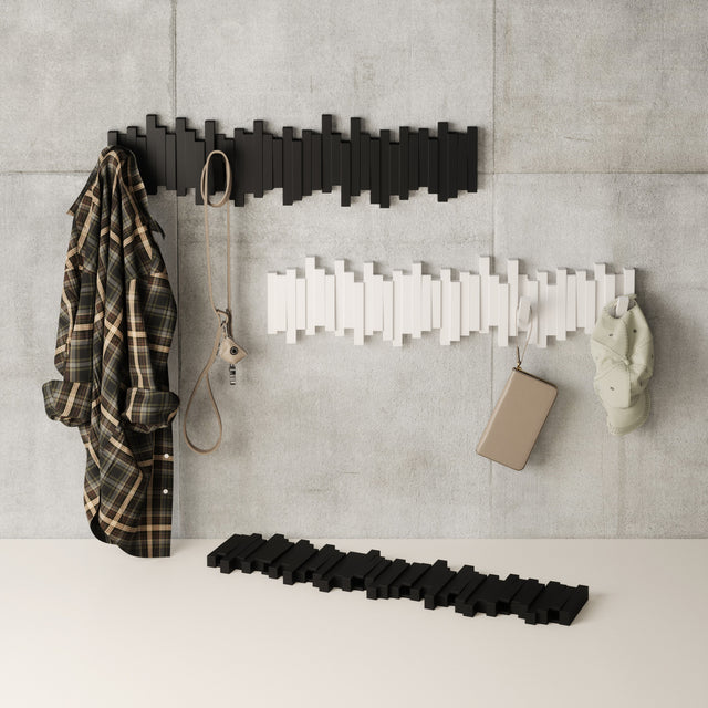 Umbra Sticks multi hook racks in black and white on a concrete wall with a coat and bag