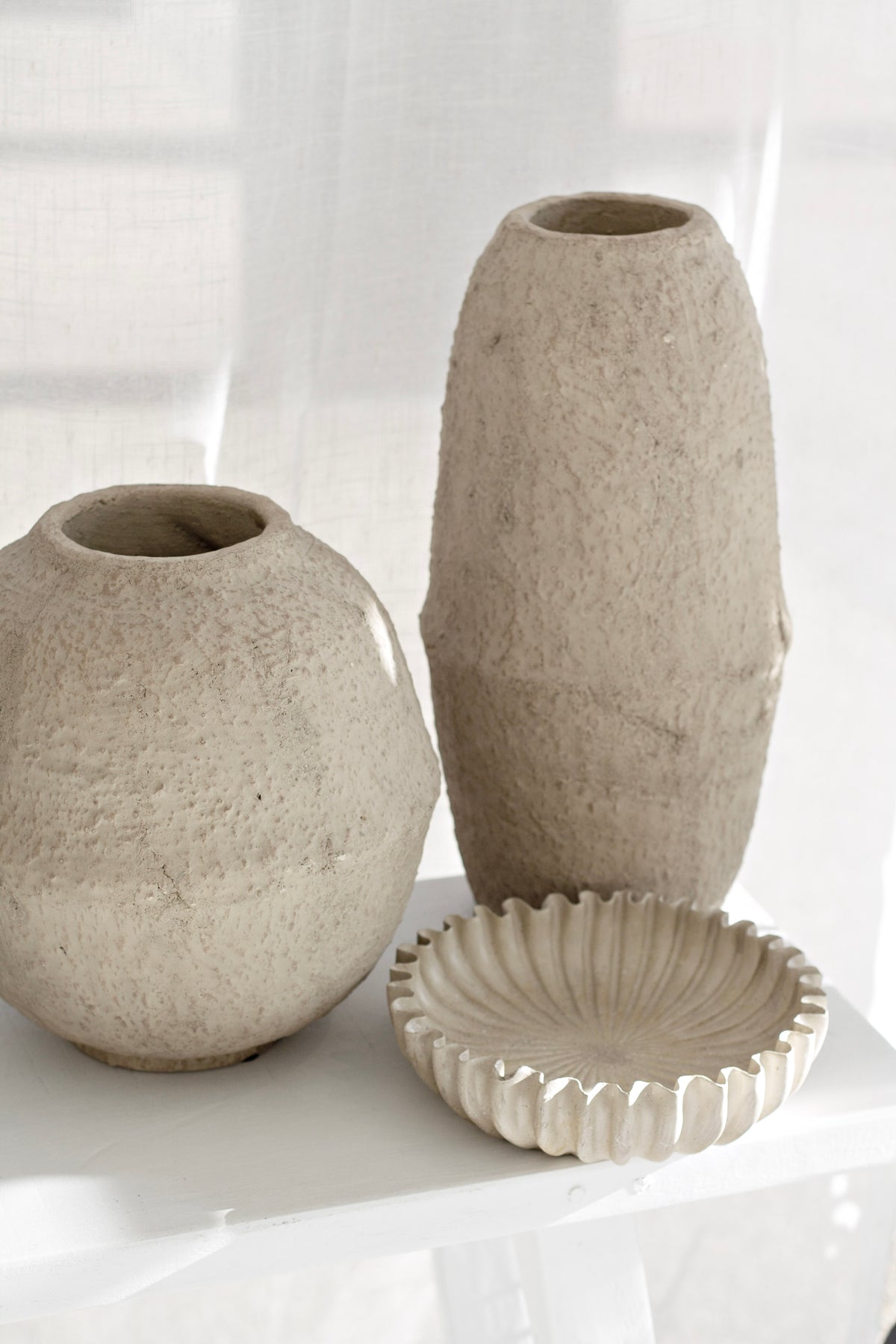 Rome Scalloped Stoneware Platter with rippled edge and natural textured finish styled with stone vases.