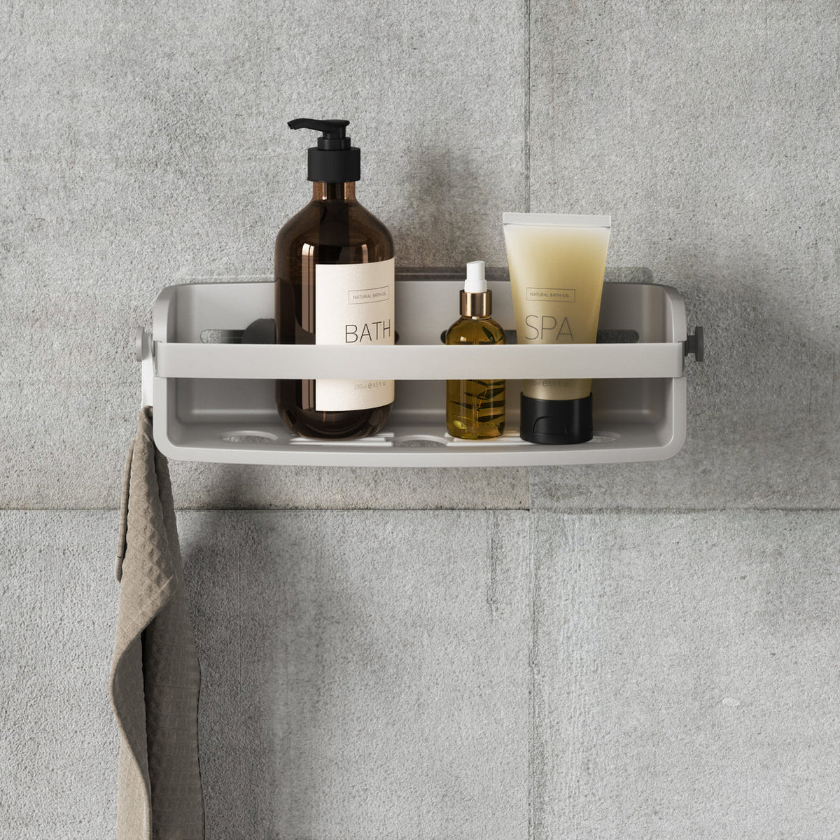 Umbra Flex adhesive shower bin in white on grey tiles holding bath and skincare bottles