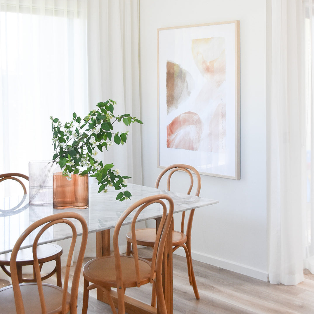 Rust Watercolour print in a white frame above a marble dining table with bentwood chairs