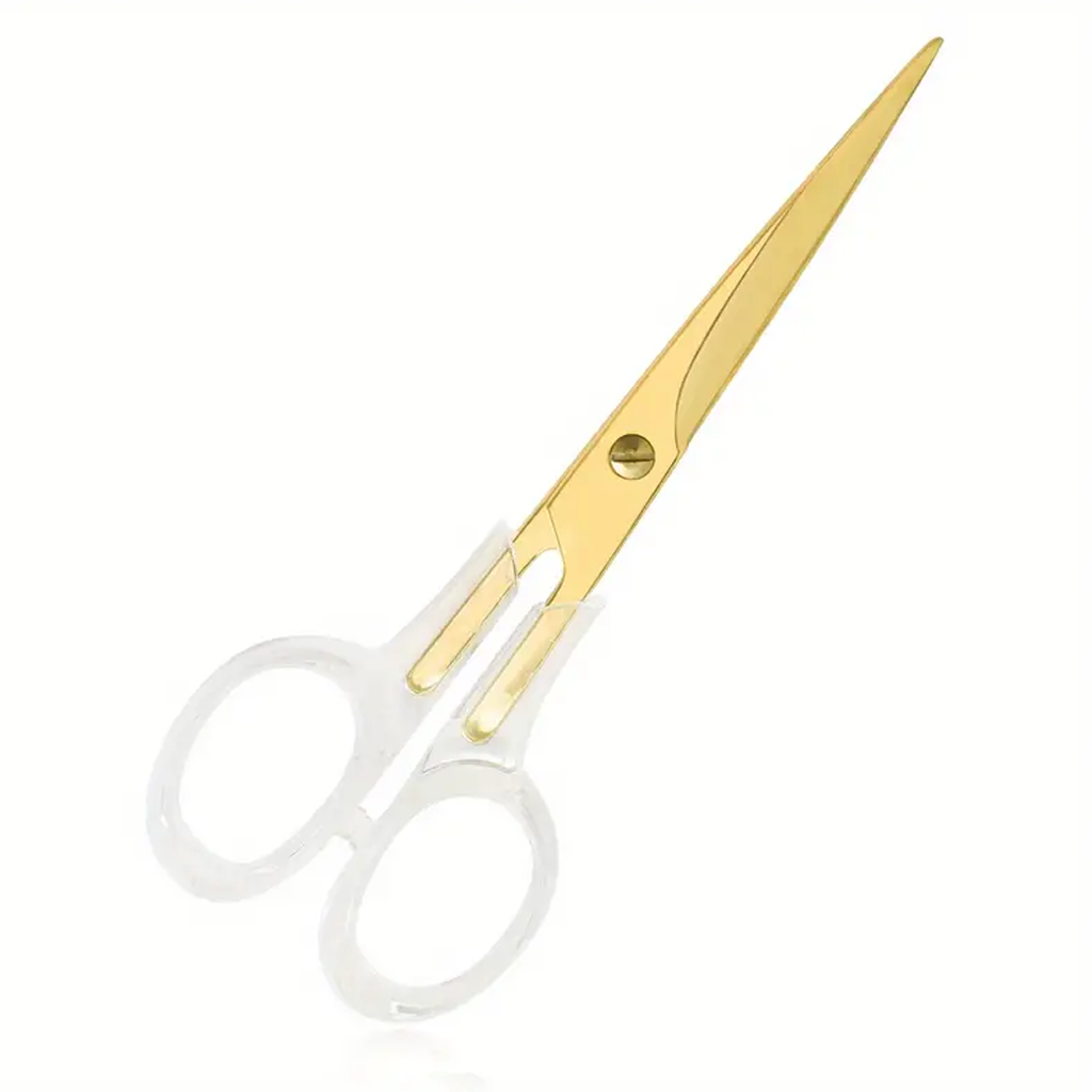 Acrylic gold scissors with clear handles styled on a desk