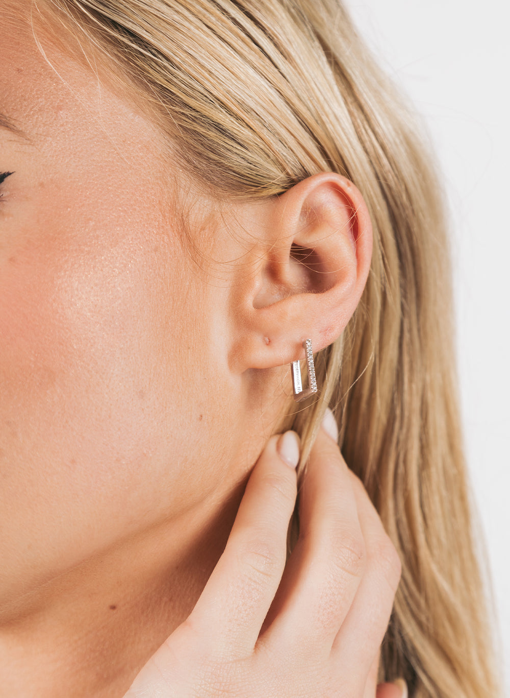 Squared Earring worn in the lobe, model's hand at her ear