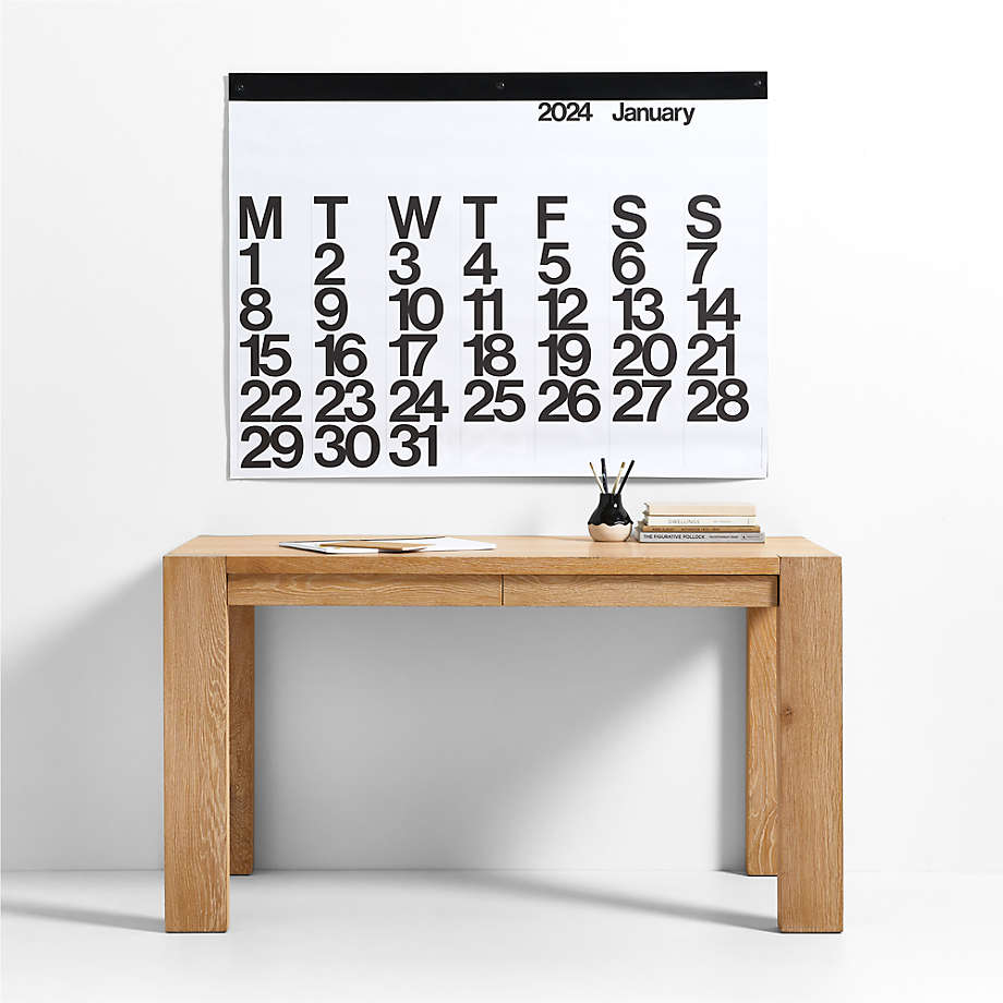 Stendig Calendar by Massimo Vignelli hanging above an oak console table styled with books and a diffuser