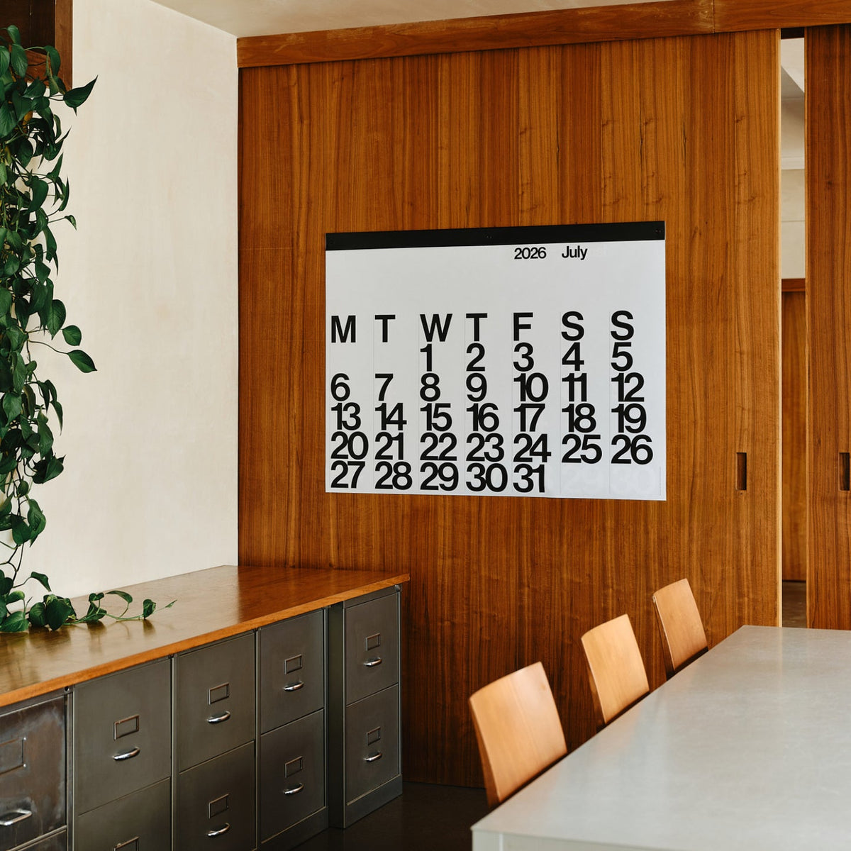 Stendig Calendar by Massimo Vignelli open to July on a timber panelled wall in a mid century styled office