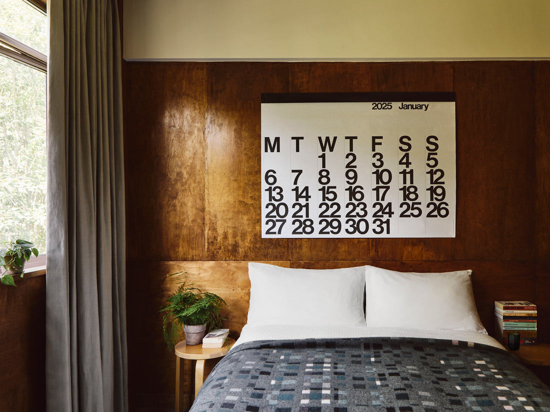 Large Stendig wall calendar above a bed in a timber lined bedroom