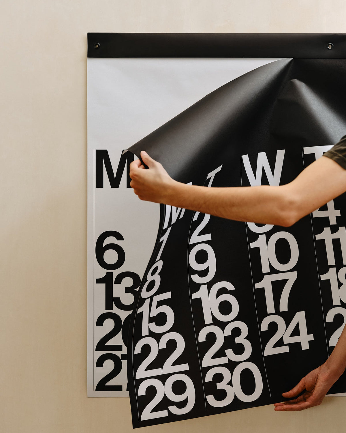 Hands holding the oversized Stendig wall calendar against a beige wall