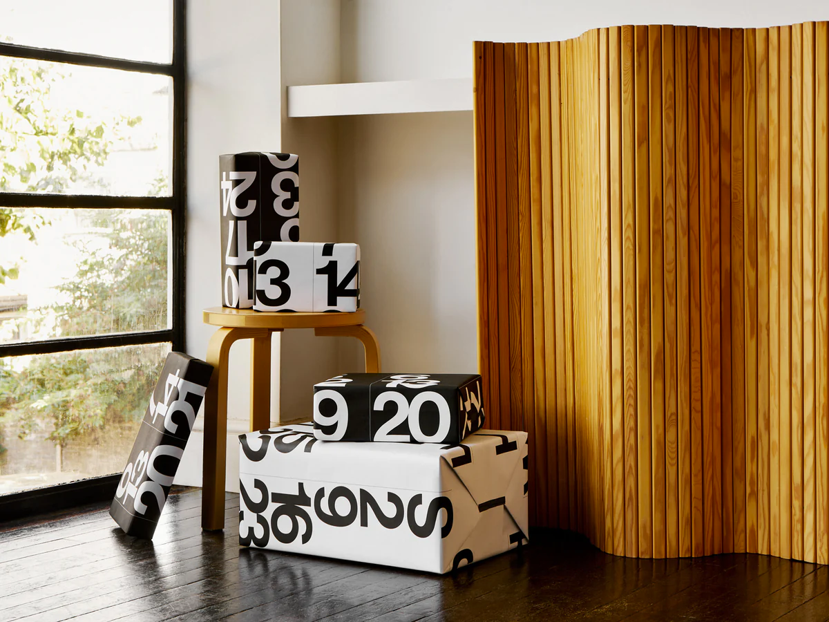 Stendig Calendar tear off pages repurposed as bold black and white gift wrap on boxes beside a timber slat screen