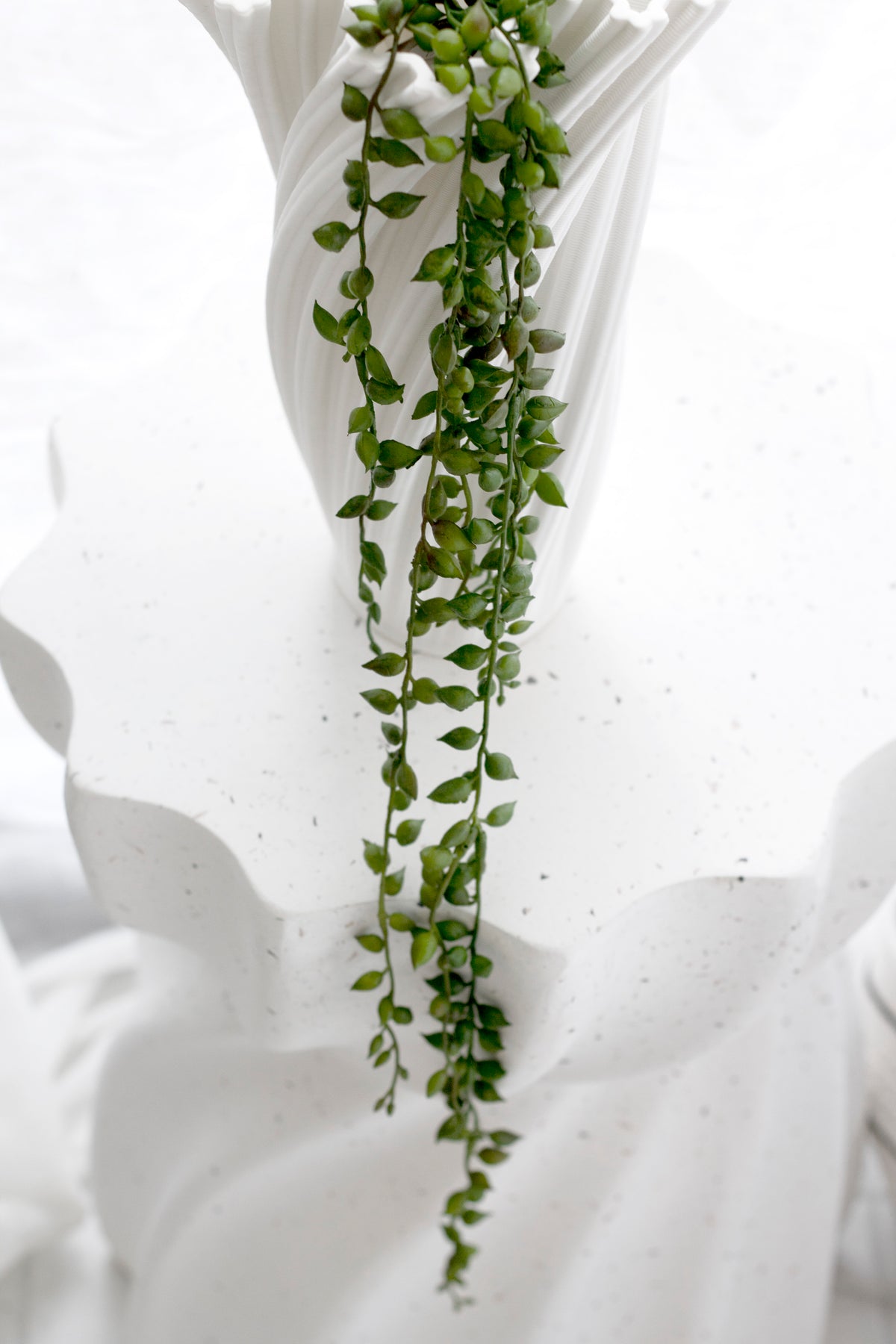 Faux string of tears trailing down the curves of a white sculptural vase